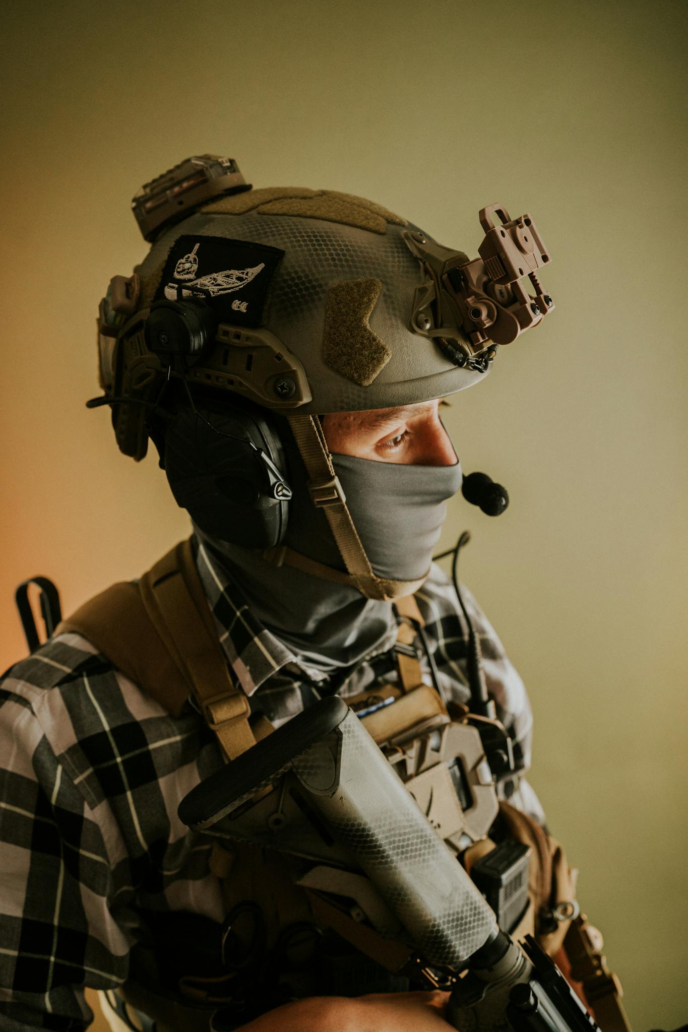 Soldier wearing tactical gear with helmet and microphone closeup.
