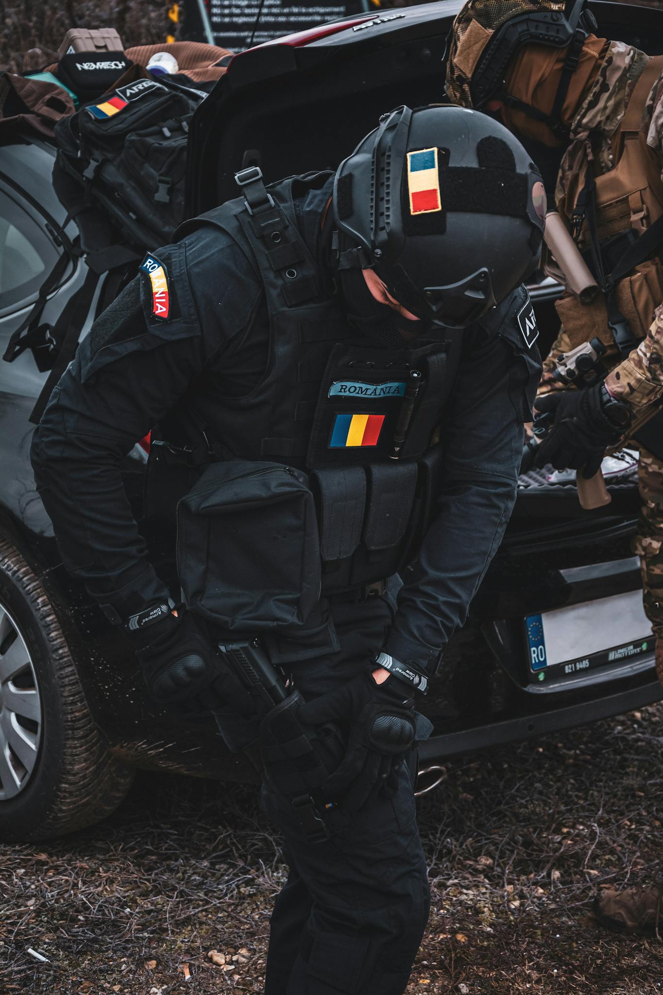 SWAT officers conducting a tactical operation near a vehicle during daytime.